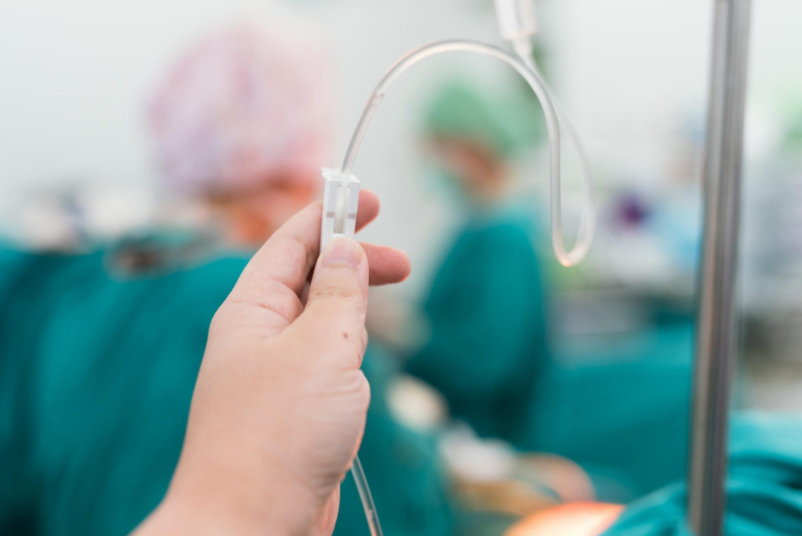 Hand hält einen Schlauch mit Infusionslösung